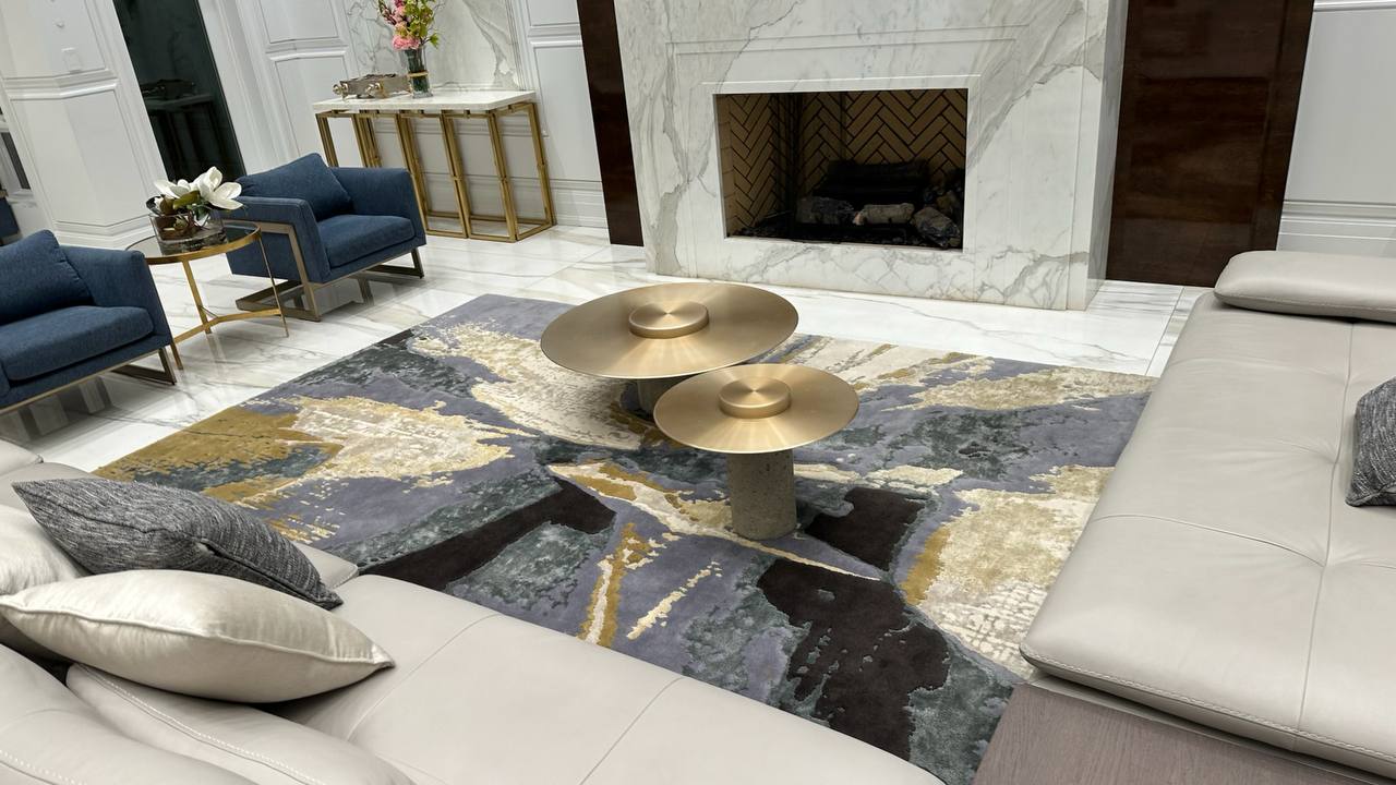 Living room with cream sofas, blue armchairs, a patterned rug and a marble fireplace.