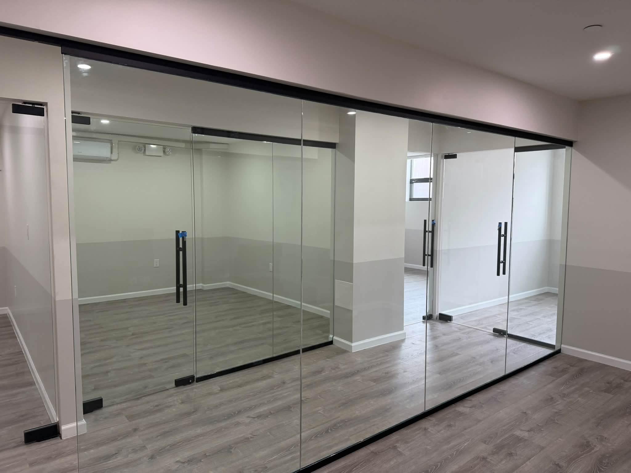 Office rooms with glass partitions and wood-look flooring.