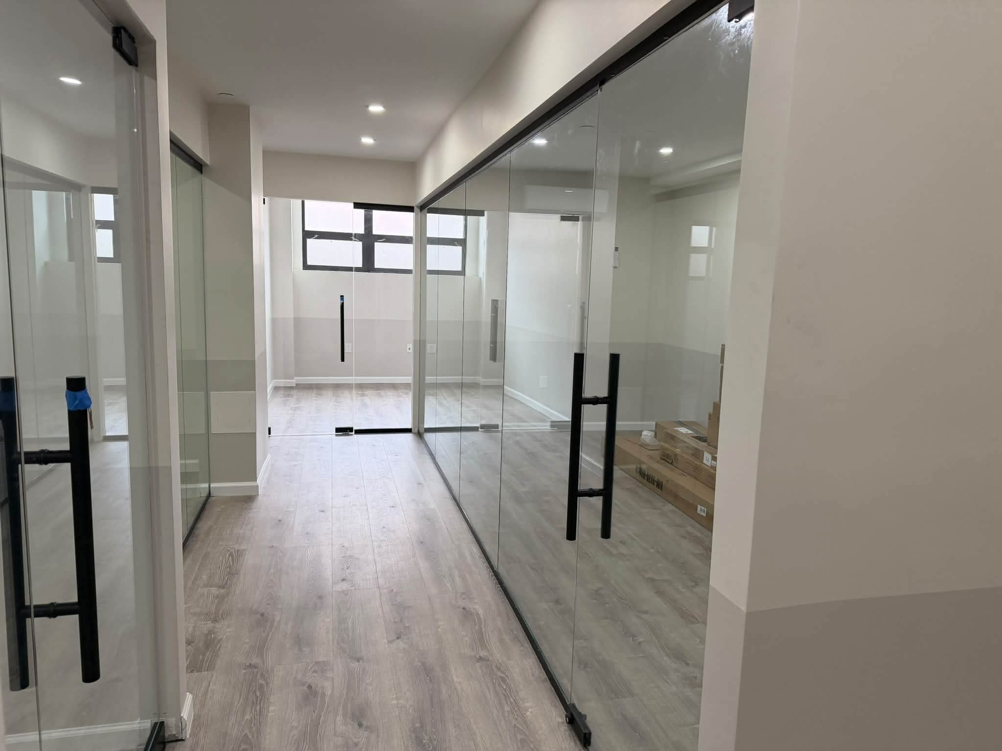 Office hallway with glass doors and clean flooring.