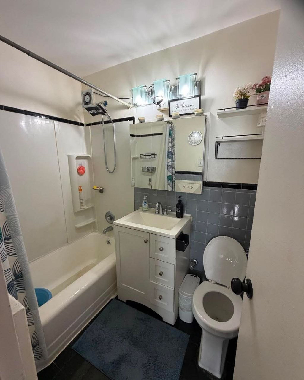 Bathroom with a bathtub, white vanity and gray wall tiles.