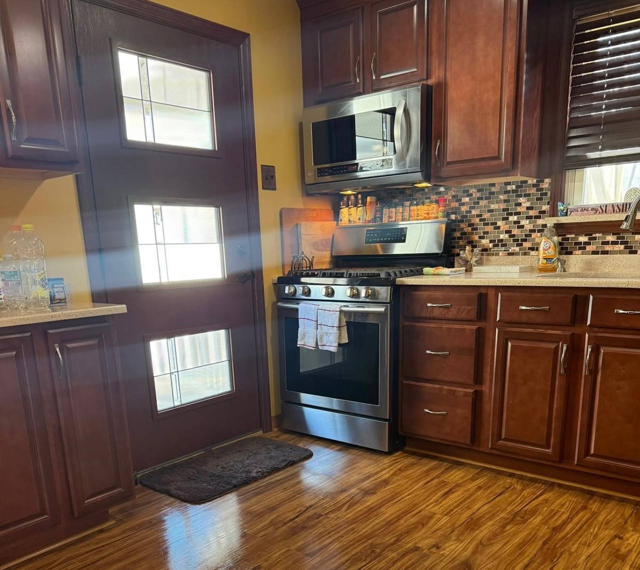 Kitchen with wood cabinets, a stainless steel stove and wood flooring.